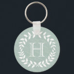Dusty Sage Green Botanical Wreath Monogram Schlüsselanhänger<br><div class="desc">Mit diesem personalisierten Minzgrün und Weiß mit Monogramm Schlüsselanhänger im Stil ergänzen. Das Design besticht durch moderne Blätter mit Lorbeerkranzen und eine stilvolle Typografie. Monogramm in der Mitte ist einfach zu anpassen. Eine elegante und nützliche Brautjungfrau,  Trauzeuge und Brautparty-Sake-Idee und ergänzt schicke Hochzeitsgrün.</div>