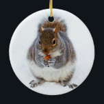 Eichhörnchen im Winter Keramik Ornament<br><div class="desc">Entzückendes Eichhörnchen, das eine Nuss im Schnee auf Weihnachtswinter-Szenenverzierung isst.</div>