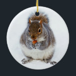 Eichhörnchen im Winter Keramik Ornament<br><div class="desc">Entzückendes Eichhörnchen,  das eine Nuss im Schnee auf Weihnachtswinter-Szenenverzierung isst.</div>