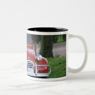 Ein alter roter Citroen 2CV Wagen mit einer lächel Zweifarbige Tasse