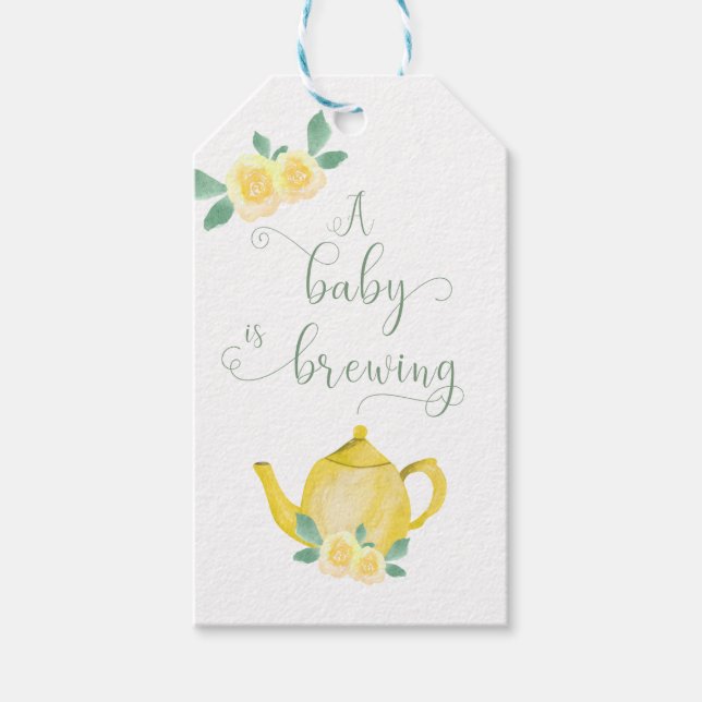 Ein Baby brät eine gelbe Teekanne mit Blumenbezug. Geschenkanhänger (Vorderseite)