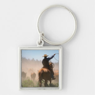 Ein Cowboy, der die Herde an einem Rind arbeitet Schlüsselanhänger