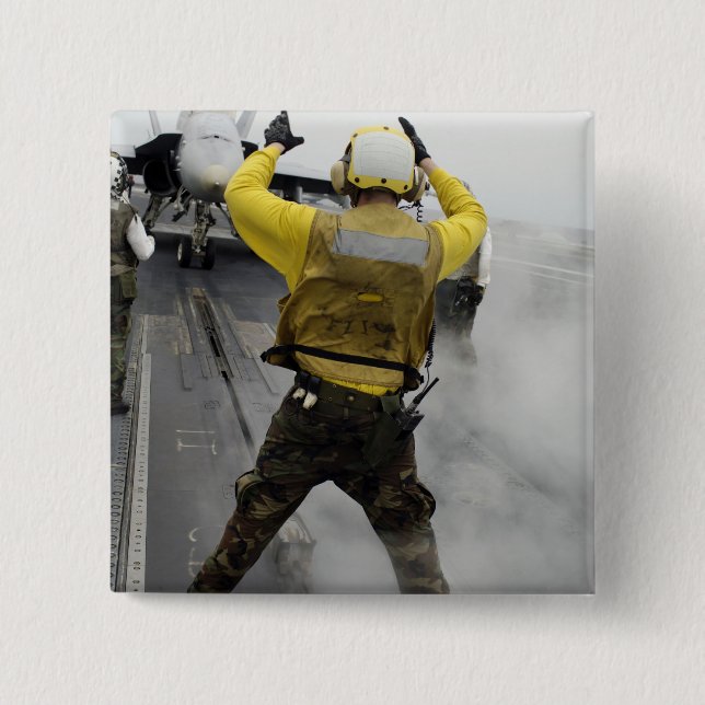 Ein Flugzeugführer signalisiert ein F/A-18C Hornet Button (Vorderseite)