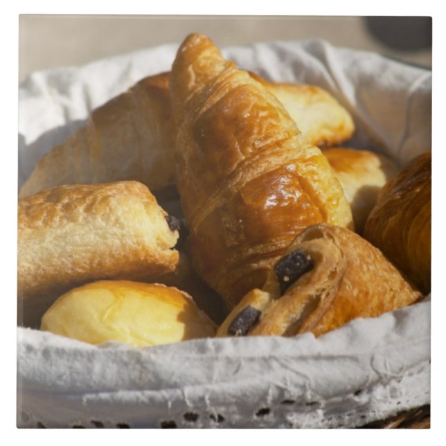 Ein Korbfrühstück mit Croissants und Fliese (Vorderseite)