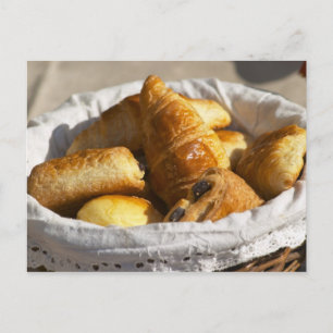 Ein Korbfrühstück mit Croissants und Postkarte