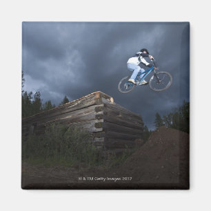 Ein Mountainbiker springt weg von einem Blockhaus Magnet
