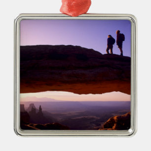 Ein paar beobachten Sonnenaufgang vom Mesa Arch in Ornament Aus Metall