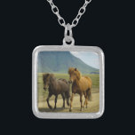 Ein Paar brauner isländischer Ponys Versilberte Kette<br><div class="desc">Ein absolut niedliches und bezauberndes Foto,  das zwei eiskelandische Ponys auf einer Schotterstraße festnimmt. Einer ist eine Bucht,  der andere ist kastanienfarben. Ihre prächtigen Mähne wehen im Wind. Eine wunderschöne Berglandschaft kann im Hintergrund gesehen werden und verleiht diesem Bild ein Gefühl des Staunens. Für Pferdefreunde und Reiter jeden Alters.</div>