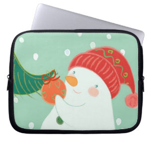 Ein Schneemann, der eine Verzierung auf einem Baum Laptopschutzhülle