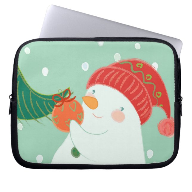 Ein Schneemann, der eine Verzierung auf einem Baum Laptopschutzhülle (Vorderseite)