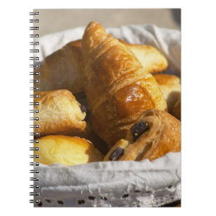 Ein Weiden-Frühstückskorb mit Croissants und Notizblock
