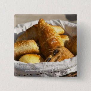 Ein Weiden-Frühstückskorbe mit Croissants und Button