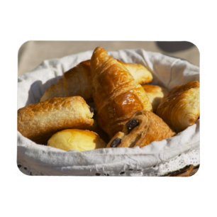 Ein Weiden-Frühstückskorbe mit Croissants und Magnet