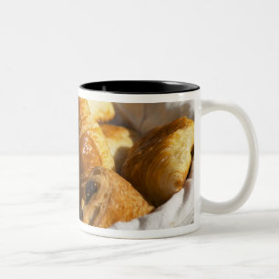 Ein Weidenfrühstückskorbe mit Croissants und Zweifarbige Tasse