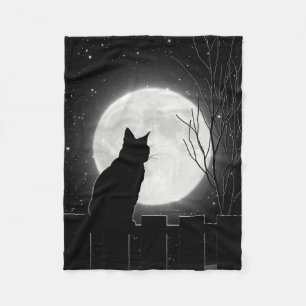 Eine stillstehende schwarze Katze und ein Fleecedecke
