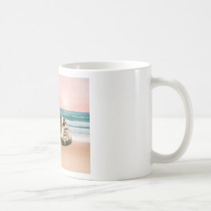 Eine süßere gestreifte Katze sitzt am Strand bei S Kaffeetasse