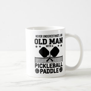 Einen alten Mann mit einem Pickleball-Schläger unt Kaffeetasse