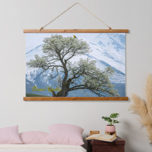 Einsamer blühender Baum und schneebedeckte Berge Wandteppich Mit Holzrahmen