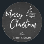 Elegant Chalkboard Script Merry Christmas Tree Runder Aufkleber<br><div class="desc">Elegantes Chalkboard Script Frohe Weihnachtsbaum Classic Round Sticker. Passen Sie es an,  indem Sie die Namen ändern. Das Design hat frohe Weihnachten geschrieben in hübschem Schriftart auf einem Kreideboden zusammen mit den Namen des Paares. Für weitere Anpassungen wenden Sie sich bitte an mich unter mypaperlove2021@gmail.com</div>