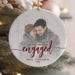 Erste Weihnachten Verlobtes Foto Rotes Skript Keramik Ornament<br><div class="desc">Gedenken Sie Ihre Verlobung mit diesem schönen modernen Sakraldekor. Der bordeauxrote Text lautet "Unser erstes Weihnachtsfest verlobt", mit dem Wort "verlobt" in fett gedruckter Schrift mit Schnörkeln vor und nach. Ersetzen Sie das Beispielbild durch Ihr Lieblings-Foto, und fügen Sie Ihre Namen und das Jahr hinzu. Mithilfe eines Farbverlaufsefilters wird der...</div>