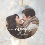 Erste Weihnachts Verlobte benutzerdefinierte Foto  Keramik Ornament<br><div class="desc">Gedenken Sie Ihre Verlobung mit diesem schönen modernen Sakraldekor. Der weiße Text lautet "Unser erstes Weihnachtsfest verlobt", mit dem Wort "verlobt" in eleganter Kalligraphie-Schrift mit dekorativen Swashes vor und danach. Ersetzen Sie das Beispielbild durch Ihr Lieblings-Foto, und fügen Sie Ihre Namen und das Jahr hinzu. Ein Filter mit schwarzem Farbverlauf...</div>