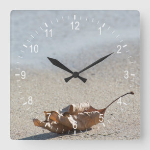 Falling leaf at sand of the sea coast quadratische wanduhr