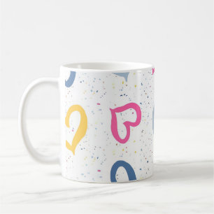 Farbige Herzchen und gesprenkelter Kaffeebecher mi Kaffeetasse