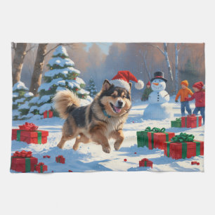 Finnischer Lapphund läuft durch Schnee mit Weihnac Geschirrtuch