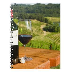 Flasche Rotwein und Glas auf dem Tisch Notizblock