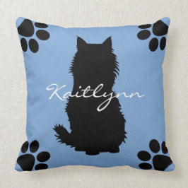 Flaumige schwarze Katze und Tatzen auf Blau Kissen