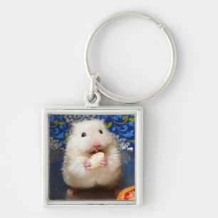 Flaumiger syrischer Hamster Kokolinka, das einen Schlüsselanhänger