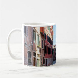 Frau in schwarzer Jacke, die auf dem Bürgersteig i Kaffeetasse