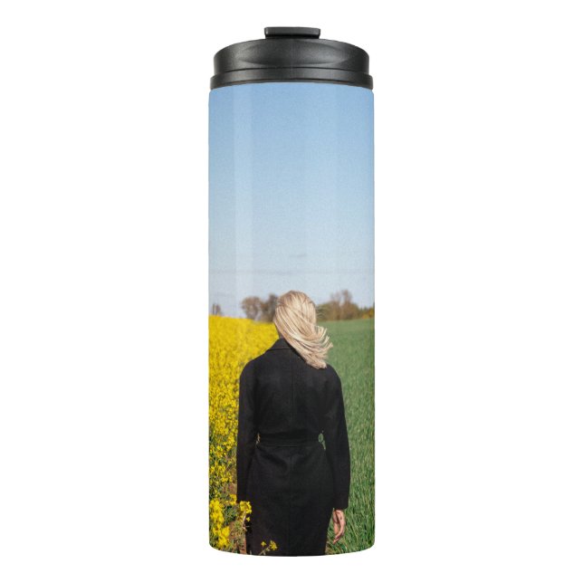 Frauen in schwarzem Mantel stehend auf grünem Gras Thermosbecher (Vorderseite)