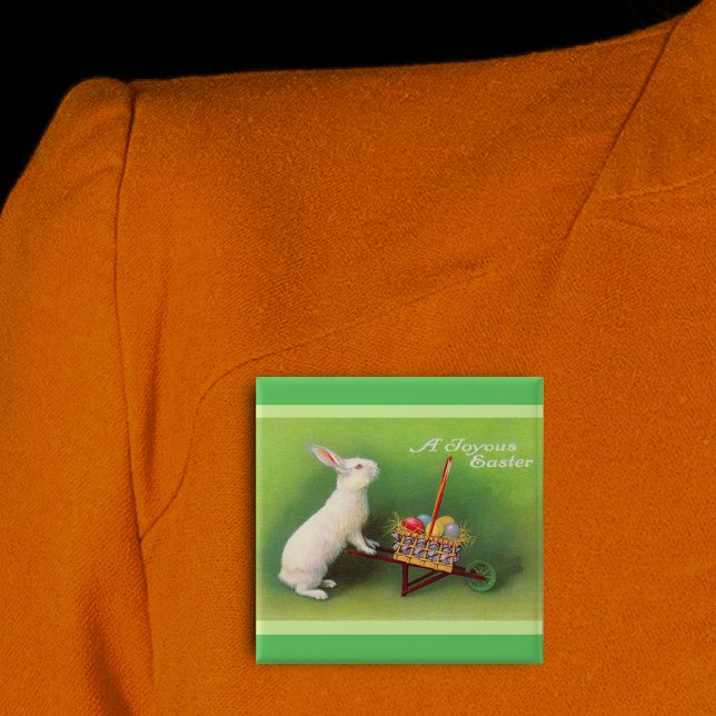 Fröhlicher Osterhase Korb Eier Button (Joyous Easter white rabbit pushing wheelbarrow coloured eggs on green pin back button.)