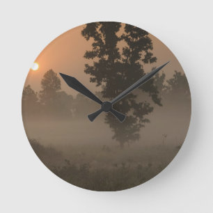 Früher Morgen, aufgehende Sonne und Bodennebel Runde Wanduhr