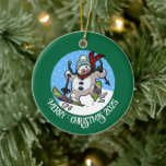 Funny Snowman frohe Weihnachten Add the Year Carto Keramik Ornament<br><div class="desc">Ein lustiges Schneemann-Ornament für Ihren Weihnachtsbaum. Verwenden Sie "Personalisieren Sie diese Vorlage", um den Text oder das Jahr zu optimieren und ein einzigartiges Weihnachtsgeschenk zu machen. Die Baumdekoration zeigt einen skurrilen Cartoon eines begeisterten Schneemanns mit Karottennase, der durch den Schnee hinunter gleitet, in Wollhut und Schal. Ein optimistisches Bild für...</div>