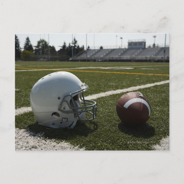 Fußball und Fußballhelm auf dem Fußballfeld Postkarte (Vorderseite)
