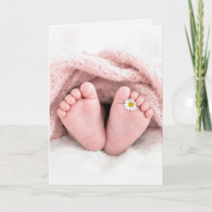 Füße eines Babymädchens mit einer weißen Margerite Karte