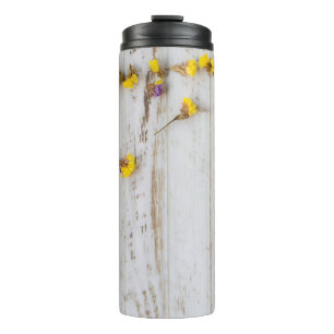 Gelbe Frühlingsblumen, weiße Putz. Thermosbecher