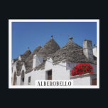 Geranium-Blume und Trulli-Häuser in Alberobello Postkarte<br><div class="desc">Postkarte mit Blume aus rotem Geranium und eine Reihe konischer,  traditioneller Trulli-Häuser mit Steindächern in einer Straße in Alberobello in Puglia,  Süditalien mit weißem Rand und dem Text "Alberobello".</div>