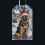 German Shepherd Winter Wonderland Christmas Joy Geschenkanhänger<br><div class="desc">Dieses festliche Design spiegelt den fröhlichen Geist der Urlaubssaison wider und besticht durch ein hübsches Jungtier mit einer Weihnachtsmannmütze. Der Hund ist eingebettet in ein winterliches Wunderland, mit einem Schneemann, einem dekorierten Weihnachtsbaum und wunderschön verpackten Geschenken. Schneeflocken fallen sanft ab und geben der Szene eine magische Touch, während die lebhaften...</div>
