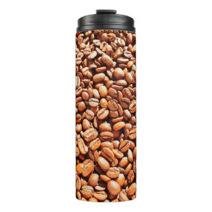 Geröstete aromatische Kaffeebohnen in Sonnenlicht, Thermosbecher