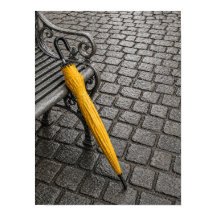 Geschlossener gelber Schirm neben Parkbank