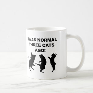 Gewöhnliche drei Katzen sind vor lustiger Umarmung Kaffeetasse