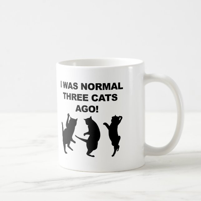 Gewöhnliche drei Katzen sind vor lustiger Umarmung Kaffeetasse (Rechts)