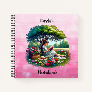 Girl Lesen eines Buches unter einem Baum an einem  Notizbuch