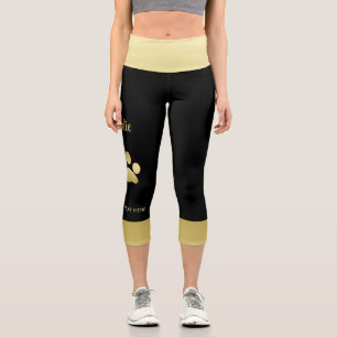 Glänzende goldene Hundepfote auf schwarzem Hinterg Capri Leggings