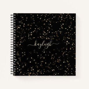Gold-Glitzer-Staub auf schwarzem Notebook Notizbuch