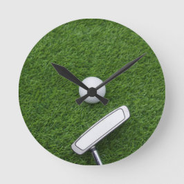 Golf ball with putter are on green grass runde wanduhr