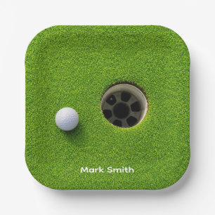 Golfball neben Loch auf grünem Rasen Golfplatz  Pappteller